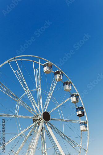 Obraz na płótnie A large Ferris wheel against a blue sky. Cabins on the Ferris wheel. w salonie