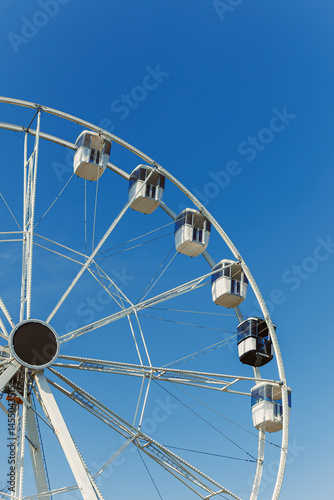 Obraz na płótnie A large Ferris wheel against a blue sky. Cabins on the Ferris wheel. w salonie