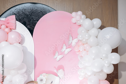Pink photo zone for children's birthday with helium white balloons. Bright celebration of children's birthday with blue balloons.