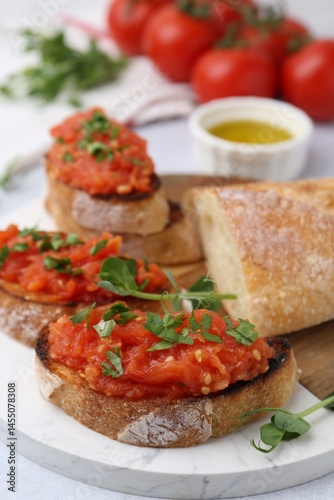 Tasty bread with tomatoes, parsley and oil on table, closeup