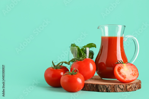 Jug of fresh tomato juice with basil and vegetables on turquoise background