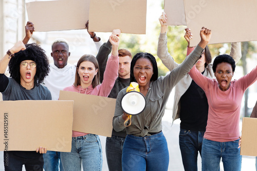International group young demonstrators striking on the street, holding megaphone and blank placards. Group of multiracial students with empty banners protesting outdoors, defending human rights