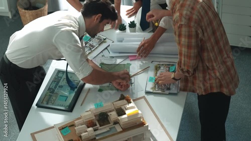 Smart architect or civil engineer writing building structure idea on note and stick on blueprint. Aerial view of manager working together with diverse colleague and show house plan. Alimentation.