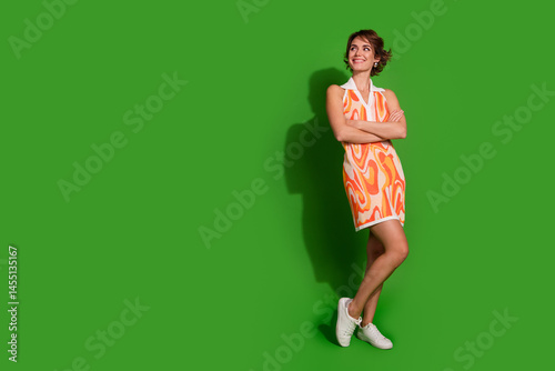 Obraz na płótnie Full body photo of lovely young lady crossed hands look empty space dressed stylish colorful garment isolated on green color background w salonie