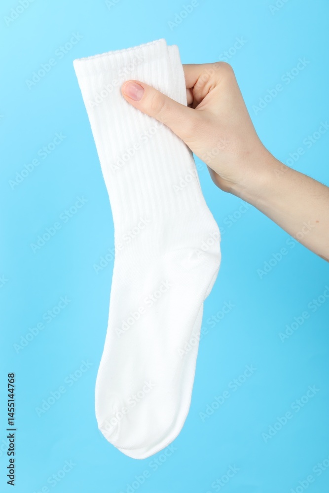 Woman with pair of socks on light blue background, closeup Woman with pair of socks on light blue background, closeup