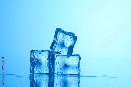 Cubes of clear ice on light blue background, closeup. Space for text