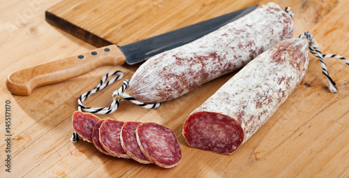 Traditional Catalan dry cured pork sausage Longaniza with sliced pieces on wooden board..
