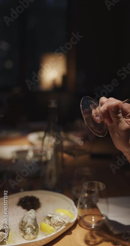 Champagne tasting, Wine glasses are on the table, stylish table setting, A man's hand holds a beautiful elegant glass with rose sparkling wine, an intimate light, a plate with oysters and lemon
