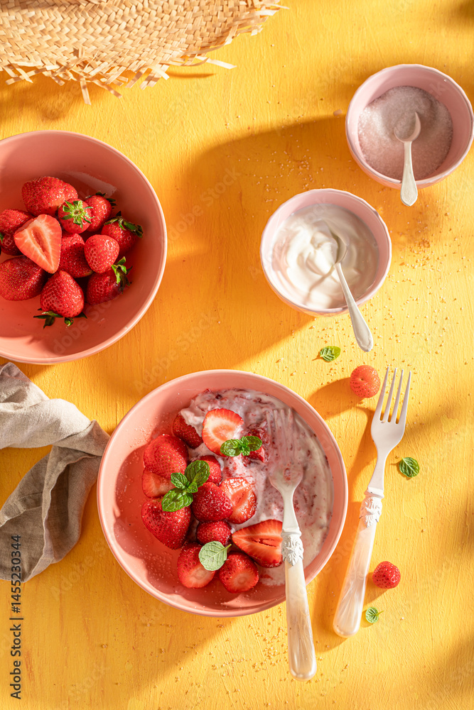 Tasty and creamy strawberries on yellow sunny table.