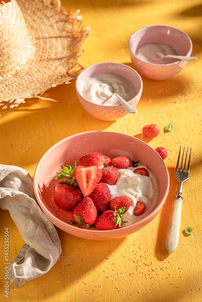 Tasty and homemade strawberries on yellow sunny table.