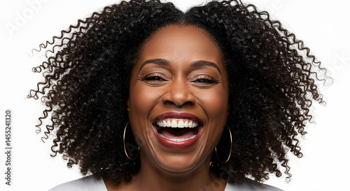 A radiant black woman with voluminous curly hair beams with laughter against a clean white backdrop.