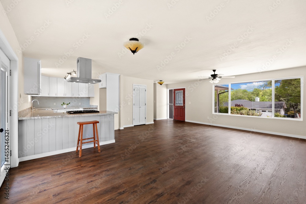 Fototapeta premium A vacant living room featuring beautiful hardwood floors and a kitchen nearby