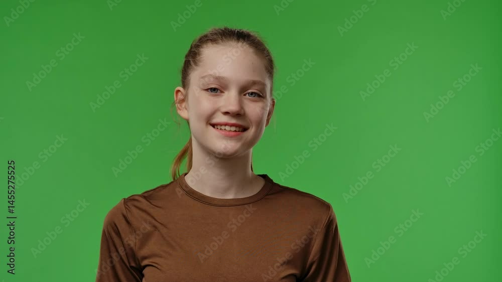 Teenage girl posing in front of camera, talking and smiling, with positive facial expression, isolated on chromakey green screen studio background. Teenage girl posing in front of camera, talking and smiling, with positive facial expression, isolated on chromakey green screen studio background.