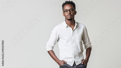 Young Ethiopian man in casual modern style, wearing glasses and white shirt, posing confidently on neutral background