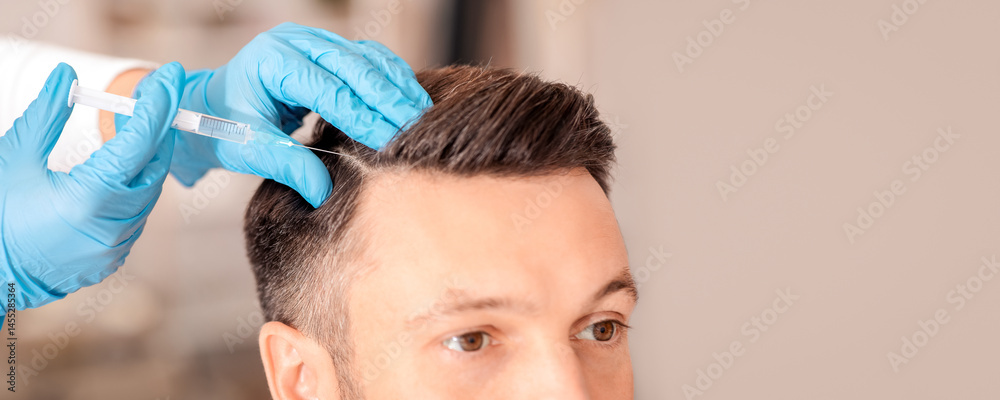 Obraz premium Handsome middle aged man getting hair treatment at beauty salon. Attractive man having mesotherapy session at beauty salon, therapist hand in protective glove making injection with syringe, closeup
