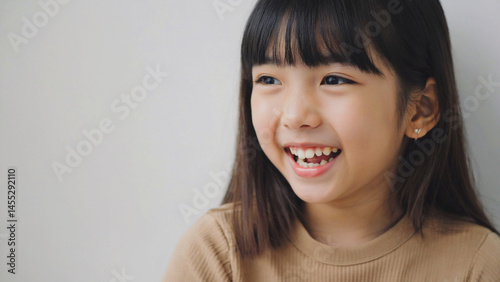 A young asian girl is smiling with joy and happiness showing her beautiful, white teeth.