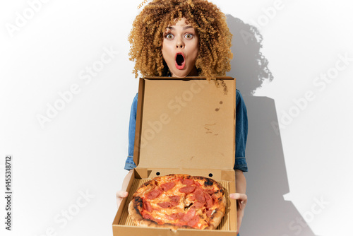 Obraz na płótnie Excited woman with curly hair holding a pizza box, expressing joy and surprise with a vibrant background showcasing her love for pizza w salonie