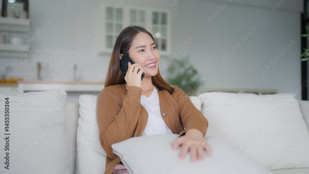 Happy young asian woman relax on comfortable couch at home texting messaging on smartphone, smiling girl use cellphone chatting Happy young asian woman relax on comfortable couch at home texting messaging on smartphone, smiling girl use cellphone chatting