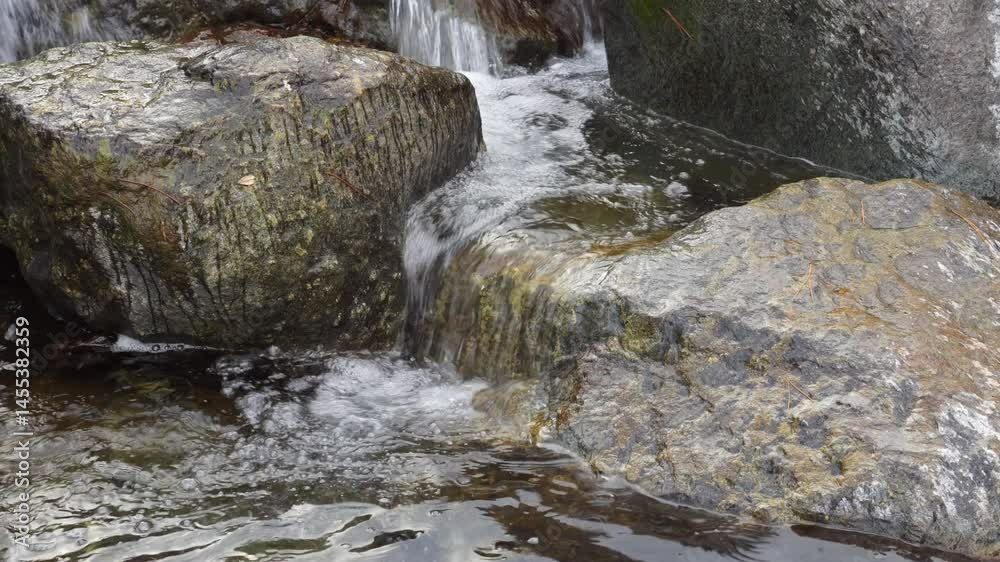 Clear Water Gently Flowing Over Rocks in a Natural Stream – Close-up Static Shot Clear Water Gently Flowing Over Rocks in a Natural Stream – Close-up Static Shot