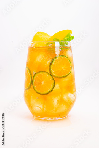 yellow peach and orange citrus drink with fresh mint leaves and ice served in clear glass on white background. High quality photo