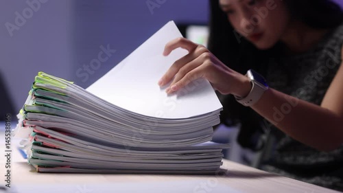 Office worker checking documents at late-night in office, analyzing financial documents.