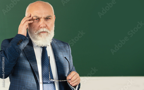 Obraz na płótnie Senior teacher in quiet classroom. Senior teacher explaining subject. Senior teacher focused on lecture. Senior teacher using chalk. w salonie