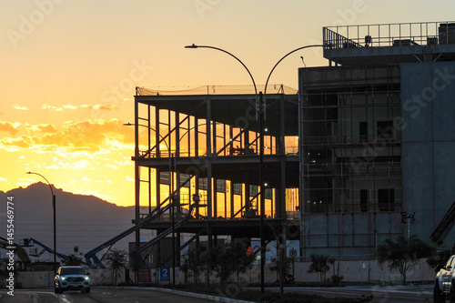 Steel frame and exterior walls of a large-scale data center under construction at sunrise, showing structural progress and utility equipment in a growing tech infrastructure zone