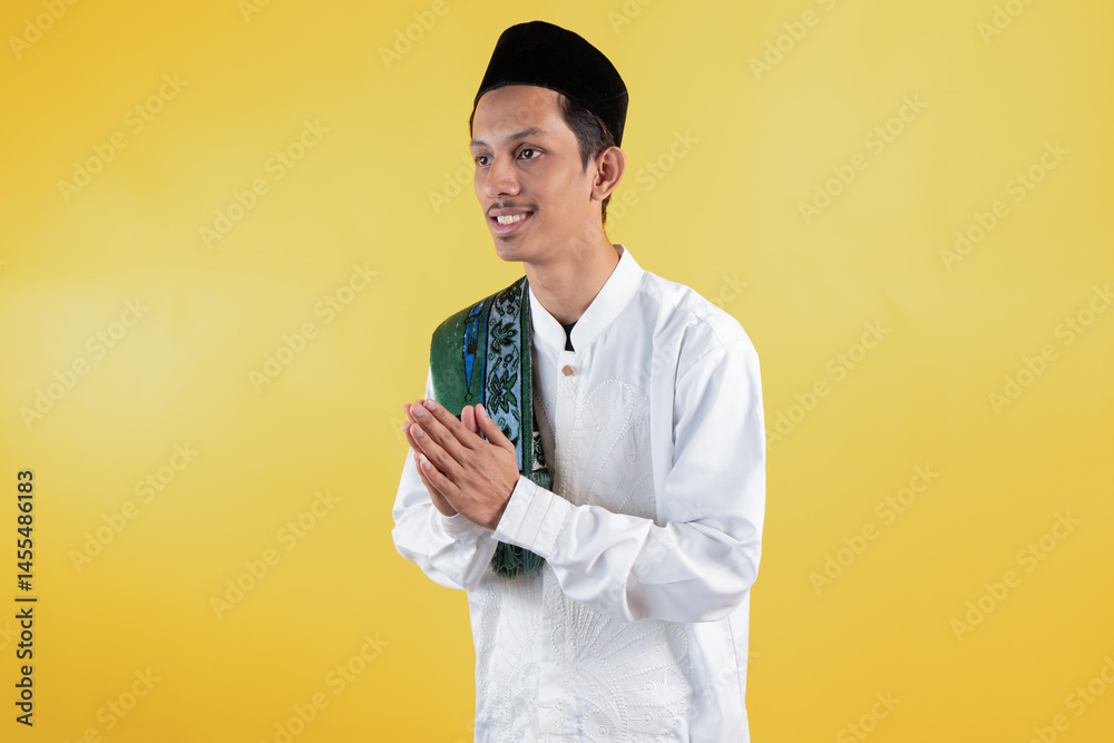 Muslim man wear white shirts with Islamic ornaments and a prayer mat on the shoulder with greeting gestures Muslim man wear white shirts with Islamic ornaments and a prayer mat on the shoulder with greeting gestures