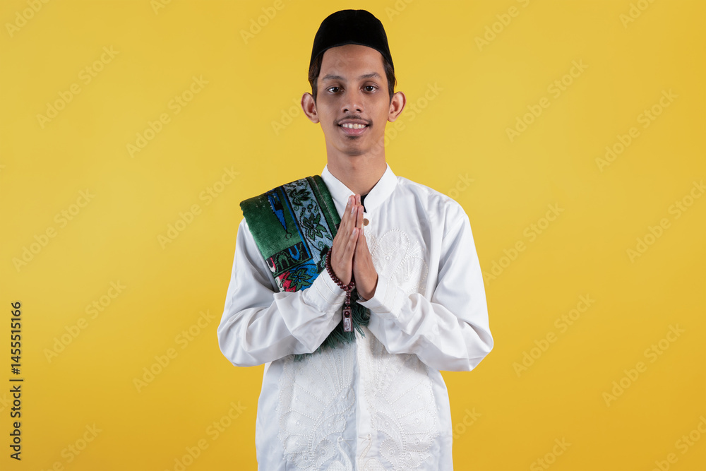 Smiling muslim man wear white shirts with Islamic ornaments and a prayer mat on the shoulder greetings Smiling muslim man wear white shirts with Islamic ornaments and a prayer mat on the shoulder greetings