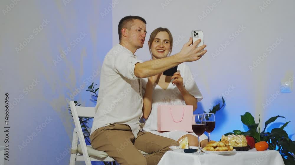 Young woman shows a gift from her boyfriend and is happy with the gift. A young couple is talking to friends on a c using a phone while celebrating Valentine's Day or an anniversary. 