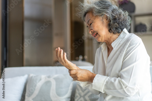 Wallpaper Mural Elderly asian woman holding wrist pain, arthritis, health issue, senior female suffering from joint pain at home, expressing discomfort, aging health problem, chronic condition indoor living room Torontodigital.ca