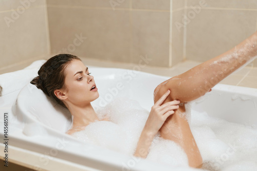 Relaxed woman enjoying a bubble bath in a modern bathroom, representing self-care and tranquility. Serenity and wellness concept for mindfulness.