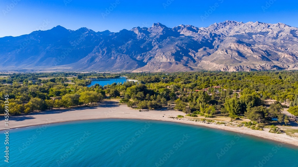 Fototapeta premium Aerial view of a serene lake with a sandy shore, surrounded by green trees & mountains