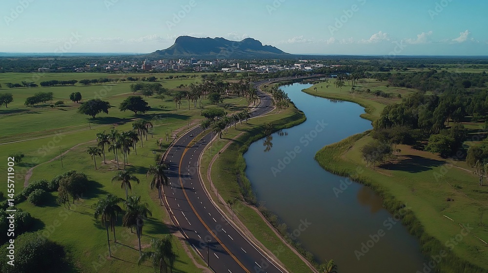 Aerial view winding road next to a calm river, mountain in background, sunny day Aerial view winding road next to a calm river, mountain in background, sunny day