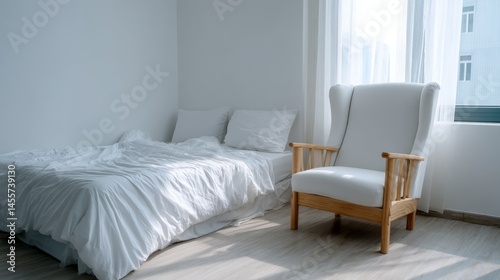 Minimalist bedroom featuring rumpled white bedding and a simple armchair bathed in natural light, creating a calm and inviting atmosphere