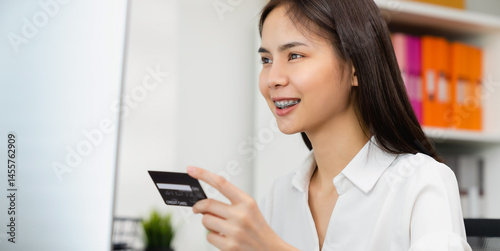 female hand holding credit card and type on laptop keyboard with online payment for shopping.