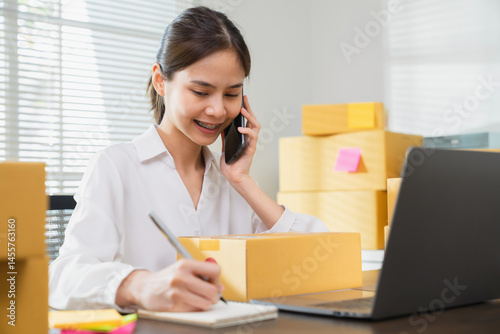 Young Asian businesswoman working talking to customers from order online and packing on the box.
