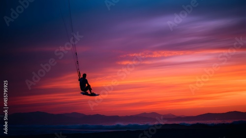 A kitesurfer takes flight at sunset, dancing on sky’s fiery canvas like a wild flame.