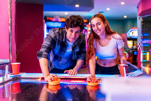Young couple playing air hockey in entertainment center