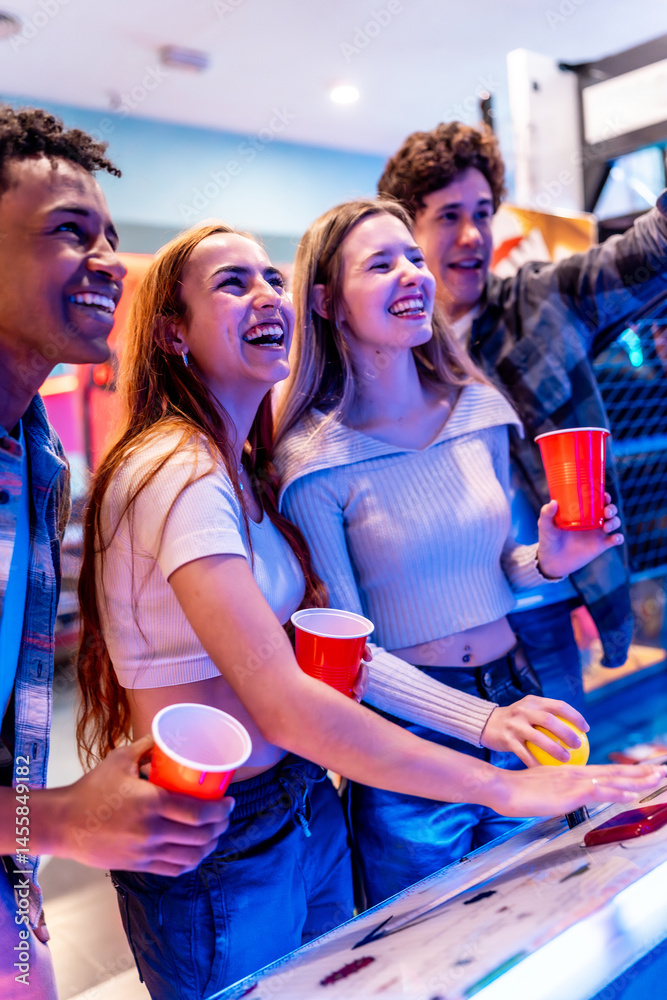Cheerful multiethnic friends enjoying arcade games on weekend night