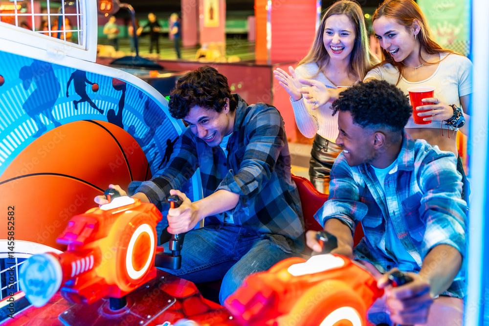 Young multiethnic friends playing arcade basketball game together