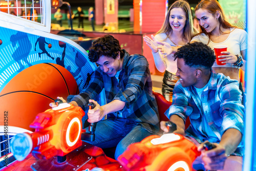 Obraz na płótnie Young multiethnic friends playing arcade basketball game together w salonie