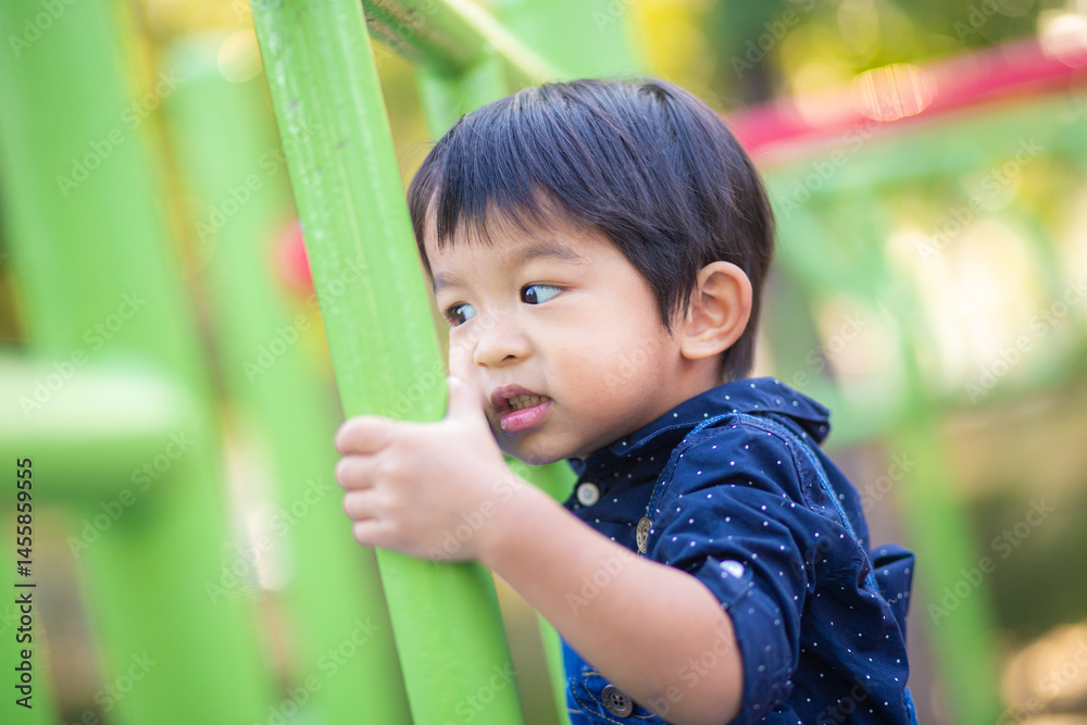 Adorable little asian 2 - 3 year boy climbing practice in playground outdoor