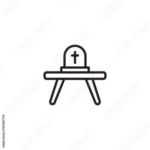A tombstone with a cross on top is placed on a table, possibly representing a memorial, remembrance, or a symbolic representation of death or loss.