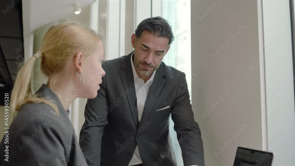 In a modern office, two professionals engage in a productive discussion, using their expertise to enhance collaboration, boost teamwork, and inspire innovation across several projects