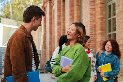 Joyful students engaging in lively conversation while sharing laughter and excitement, showcasing the essence of friendship and camaraderie. Teenage classmates talking in the university campus. High