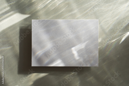 Empty paper card with sunlight shadows on glare green background. Natural abstract aesthetic mockup with caustic effects for design and presentation.