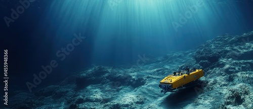 Yellow remote operated vehicle explores ocean floor under beams sunlight.