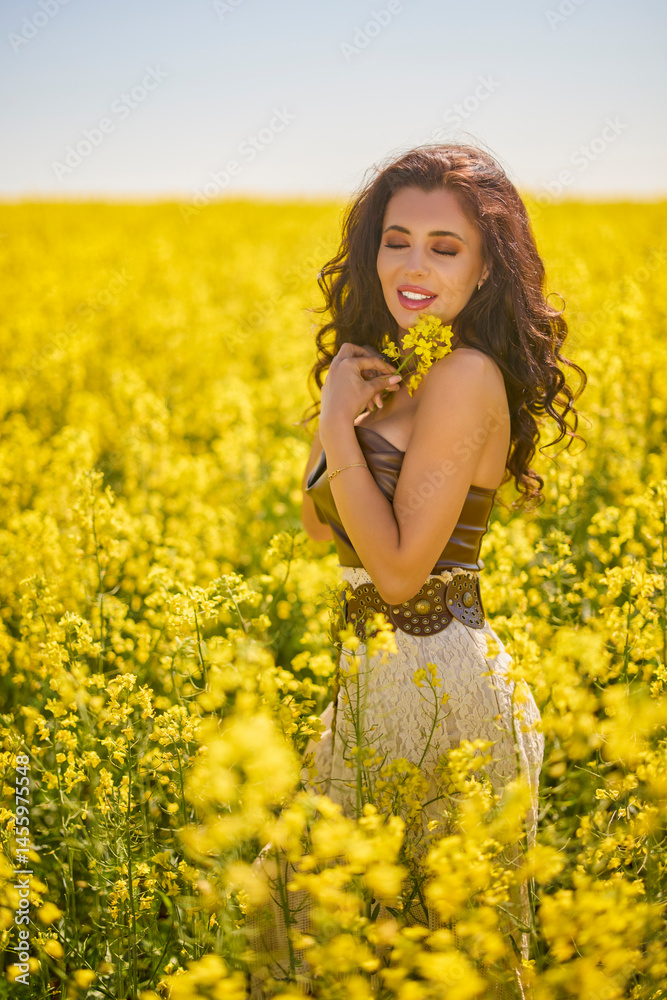 beautiful woman posing in a field of blooming rapeseed