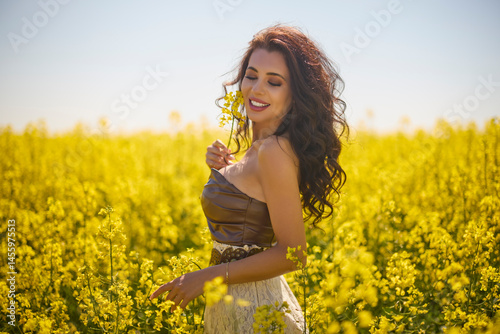 beautiful woman posing in a field of blooming rapeseed